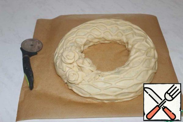 Transfer the roll to the parchment in the form of a ring. The joint is decorated with roses. Leave to rise for 15-20 minutes.