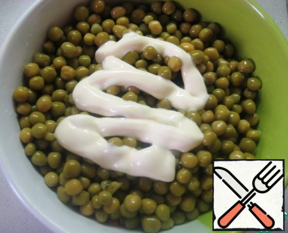 Add the canned green peas (pre-drain the liquid from the jar) and season with mayonnaise. Carefully mix the salad and you can serve it to the table.
