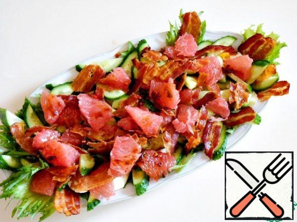The cooled and dried bacon was divided into random pieces and laid out on the entire surface, then - the rest of the grapefruit and the remaining dressing on top.