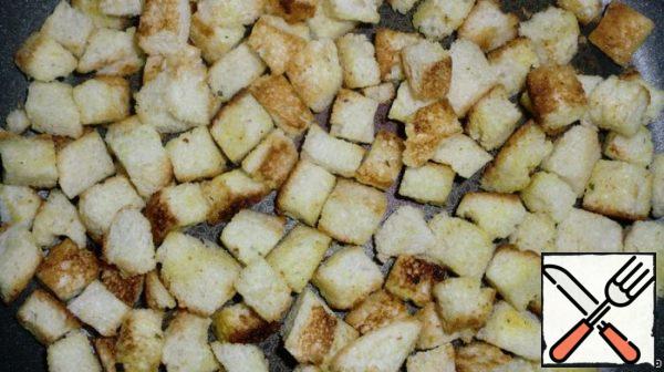 Prepare crackers: cut off the crust from the loaf, cut the flesh into cubes. Place the sliced loaf on a baking sheet, drizzle with butter and sprinkle with seasoning or salt. Bake on a low heat until Golden brown. You can make crackers in a pan, as I did, but crackers from the oven are tastier.