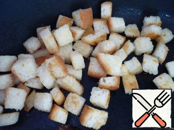 Prepare croutons: cut the bread into small cubes and fry in vegetable oil until golden brown.