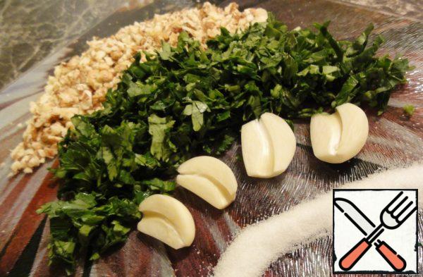 Chop walnuts with a knife or rolling pin, and finely chop the greens. Cut the garlic cloves in half, remove the green centers, so the garlic in the salad will not be too "vigorous".