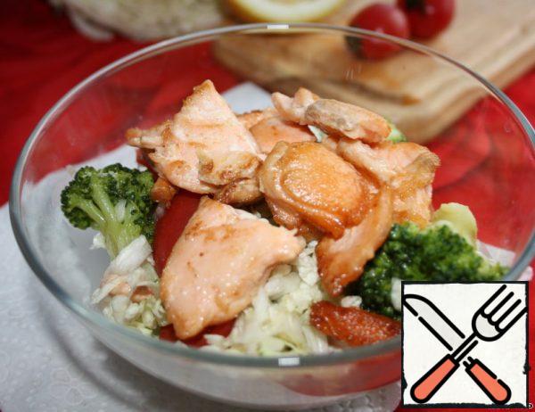 Put the broccoli, Peking cabbage, tomatoes and pieces of salmon in a salad bowl...