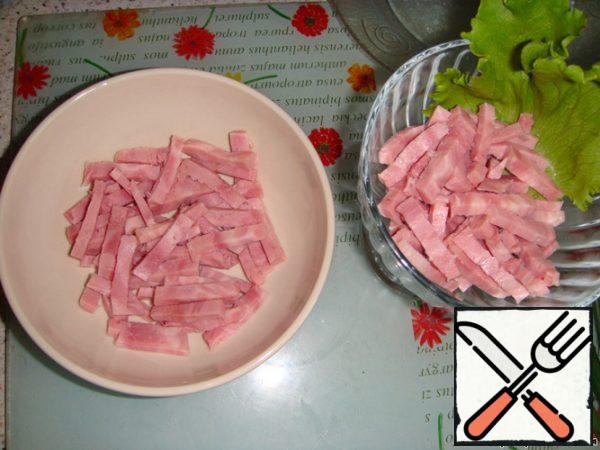 Let's start collecting salad! The first layer is spread with sliced ham, then a layer of mayonnaise.
