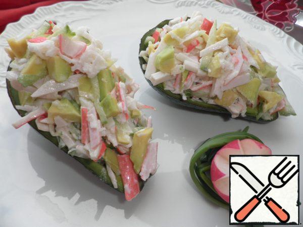 Cut the crab sticks into small strips.
Add a finely chopped cucumber to them.
Peel and grate the radish on a coarse grater and add it to the crab sticks.
Cut the avocado in half, remove the stone and carefully remove the avocado pulp, which is finely chopped and add to a plate with the rest of the ingredients.
Season everything with mayonnaise, mix and pour the avocado halves.