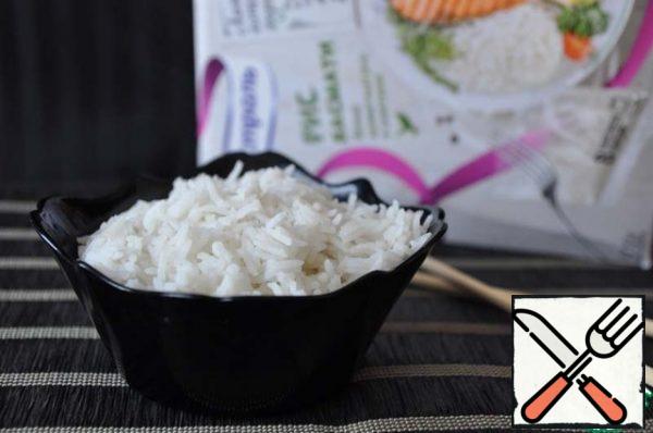 Take out a bag of rice from the water with a fork, let the water drain, tear off the edge, put it in a plate (bowl).