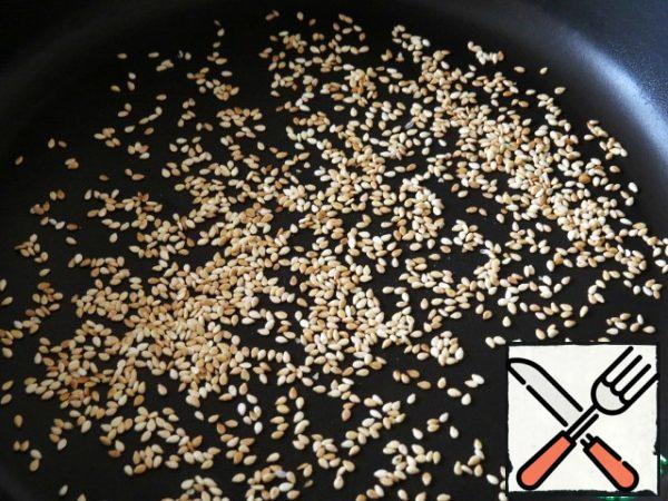 Sesame seeds are fried in a frying pan until light golden brown.