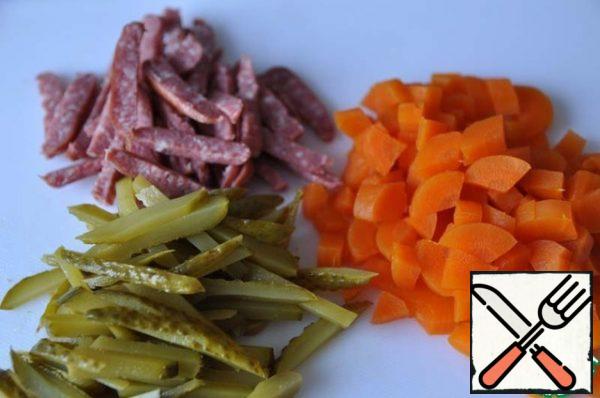 Pre-boil the carrots, clean, cut into cubes.
Cut the smoked sausage and pickles into thin strips.