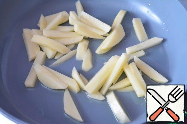 Peel the potatoes and cut into strips. Fry the potatoes in a hot frying pan with the addition of oil.