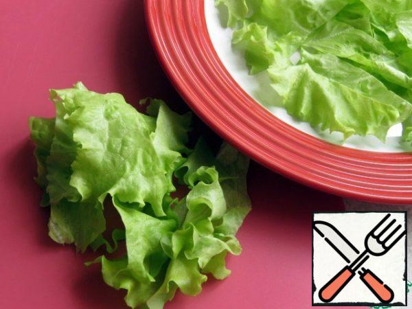 Lettuce leaves are torn or coarsely cut and placed on a dish.