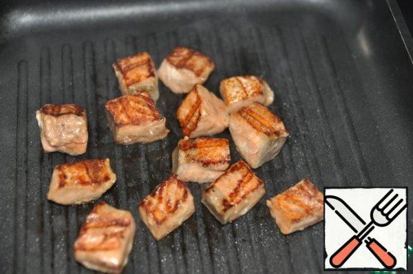 Marinated salmon is fried in a grill pan for 2 minutes on each side.