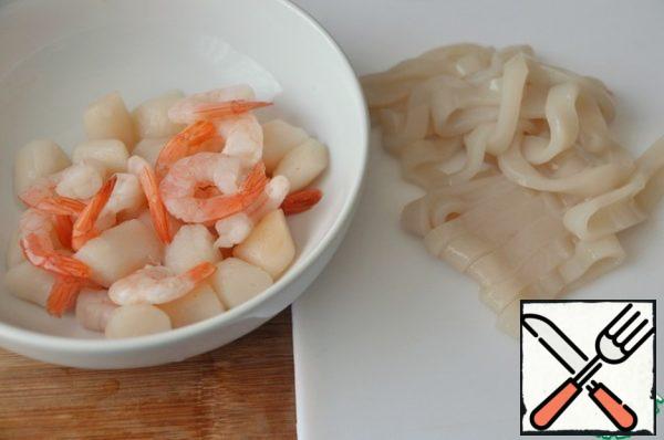 Let the prawns and scallops thaw at room temperature.
Clean the squid, cut into strips of 5-8 mm.