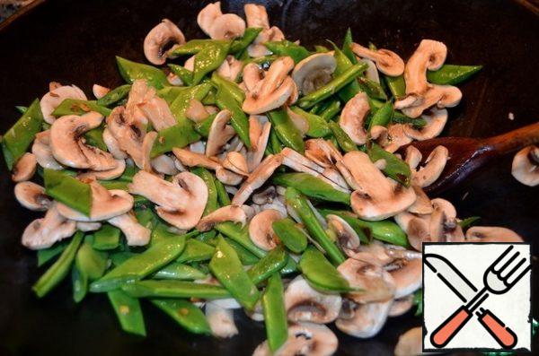In the hot oil, quickly fry the green beans, 2 minutes, add the ginger and mushrooms. Cook for another 2 minutes, constantly stirring and slightly tossing the ingredients in the air – so they have time to cool slightly and form a crisp when in contact with the wok.