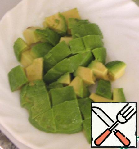Cut the avocado in half, get the stone, cut the flesh into cubes.