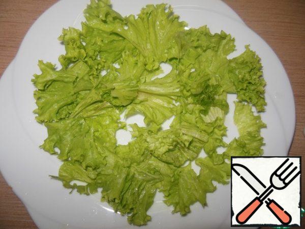 On a large dish, tear the salad leaves, and lay them out in any order.