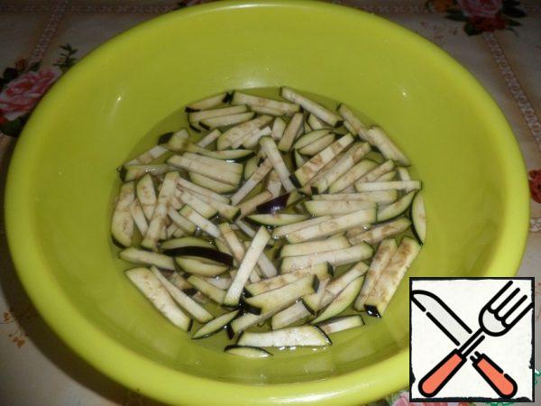 Put the sliced eggplant in a Cup and fill with cold water. Leave for 10-15 minutes.