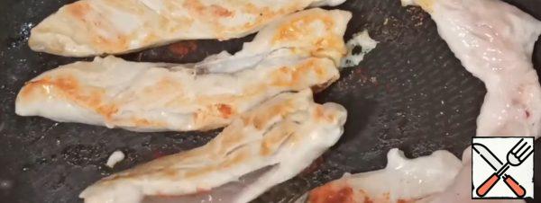 Cut the chicken fillet into strips. Put the strips on a dry hot frying pan, add salt, sprinkle with dry garlic and paprika. Fry for 3 minutes, turn the fillets over, also add salt and sprinkle with spices. Fry for another 3 minutes. The fillet turns out to be very juicy and tender. Let cool slightly and slice at an angle.