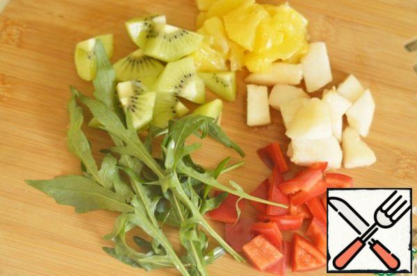 Peel and core the pear, chop the orange, peel the kiwi and remove the seeds from the pepper. Chop the fruit and pepper. Wash the arugula.