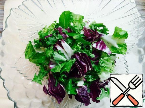 Lettuce leaves are torn and put in a salad bowl.