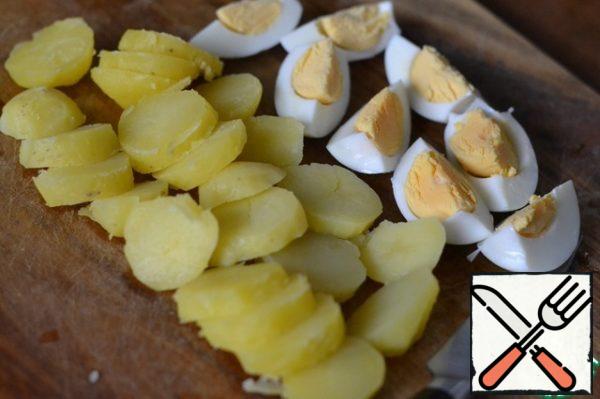 Boil potatoes in a uniform. Clean. Cut into slices.
Hard-boiled eggs. Clean. Cut into quarters.