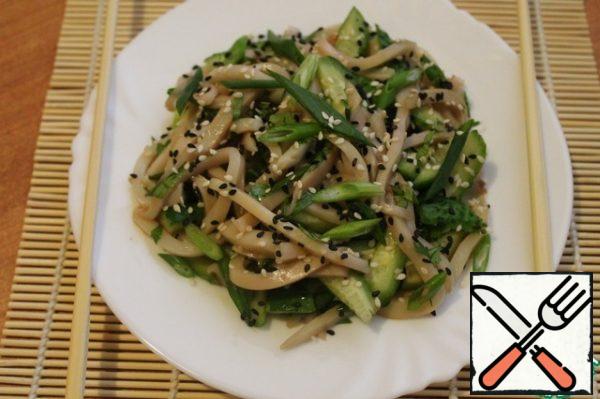 In a bowl, mix the greens, squid and cucumbers, pour soy sauce and sesame oil. Sprinkle with a mixture of black and white sesame. Asian-style squid salad is ready!