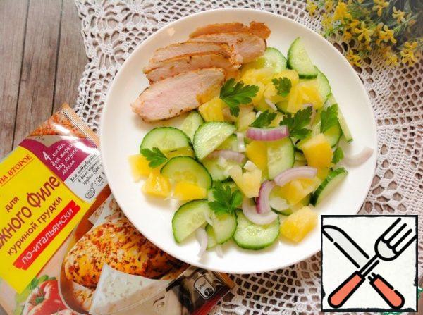 Put the red onion, cucumber slices and pineapple in a bowl, add the dressing and mix. Put the salad and chicken pieces on a serving dish and sprinkle with herbs.