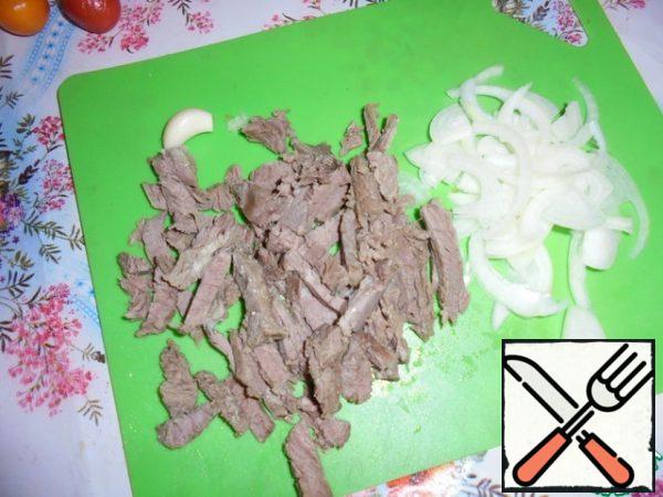 Peel the onion and cut it into half rings. Cut the boiled lamb into thin strips.