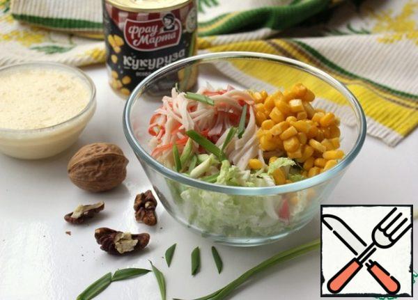 In a bowl, combine the crab meat, Peking cabbage, and corn. Add chopped green onions and walnuts. Walnuts pre-dry in a pan and chop in a convenient way: roll with a rolling pin, grate on a fine grater, chop with a knife.