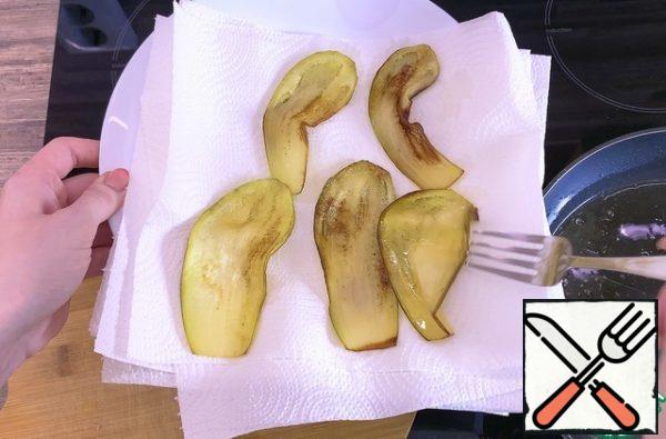 Peel the eggplants, cut them into thin strips and fry them in vegetable oil (you can also bake them in the oven), then blot them on a paper towel.