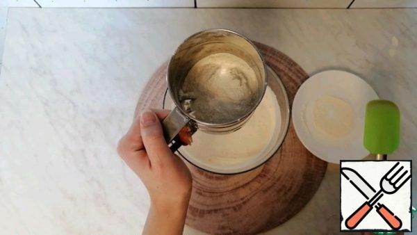 Then I take the flour and sift it through a sieve in three sets.