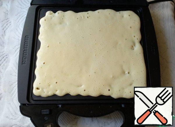 Turn on the waffle iron and wait until the red indicator lights up ready to work.
Pour the dough, lower the lid.