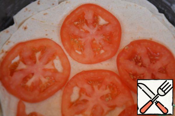 Cover the top with a second pita bread. Lay out the tomatoes.