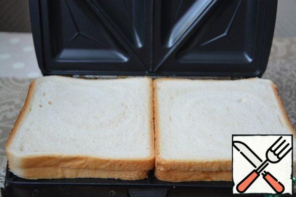 Install the sandwich panel in the slow cooker. Turn it on and wait for the notification that it is ready to work (the green indicator will light up). Put the bread on a baking sheet, close the lid.