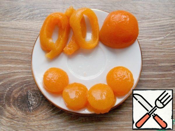 From the halves of canned apricots, we cut out small round pieces so that they fit our egg blanks as yolks.