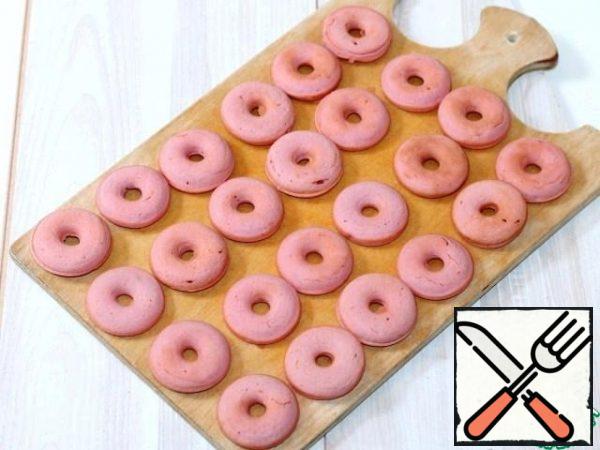 Baked doughnuts with a silicone spatula are transferred to a cutting wooden Board.