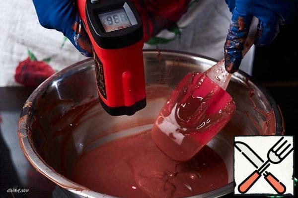 Pour the chocolate back into the bowl. Stirring with scooping movements, bring the chocolate to a temperature of 33*C. I'm measuring with an electronic proximity pyrometer. You can buy it at any construction store.