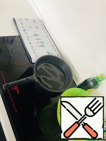 Put the pan on the stove. We heat it up well and reduce the heating power by half. Pour vegetable oil into the pan. We will also prepare a Board with a paper towel. Will spread our pancakes on it.