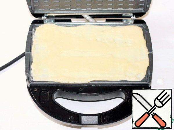 Open the lid of the multi-Baker. The baking dish is not greased with oil. Evenly spread the dough on 1.5 tablespoons per 1 serving and quickly spread on a warmed mold. Close the lid.