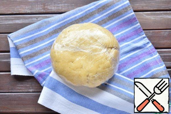From the resulting crumbs, assemble the dough into a single lump. The dough turns out to be heterogeneous and layered. Do not knead it for a long time, otherwise the oil will begin to melt from the heat of your hands.
Wrap the dough in plastic wrap and put it in the refrigerator.