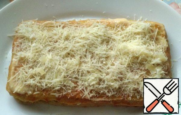 Then lay out the second cake, smear with sour cream and garlic. Grate the cheese on a fine grater.