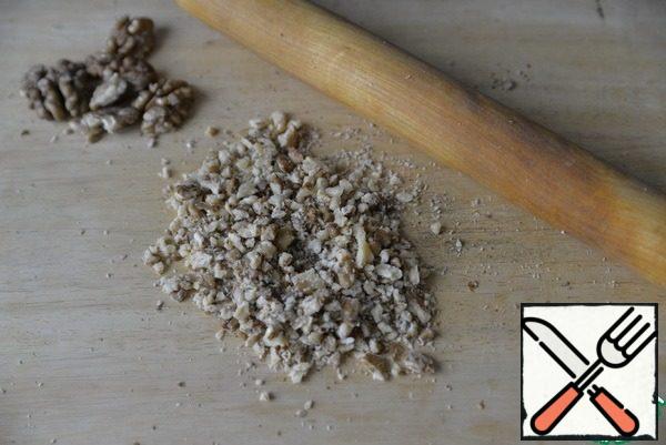 Walnuts are dried in a frying pan and crushed into crumbs with a rolling pin.