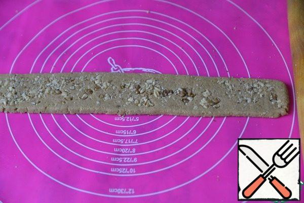 Remove the dough from the refrigerator, sprinkle generously with nuts and roll them out with a rolling pin so that they do not crumble.
