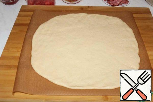 Knead a little dough. Roll out in a circle 7 mm thick and transfer to parchment.