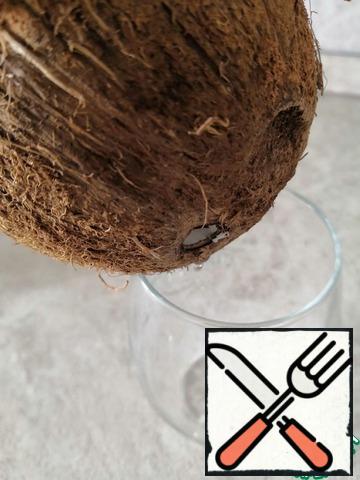 Prepare the coconut. Make a hole with a knife and drain the liquid.