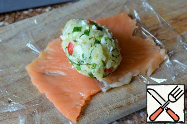 Put the salmon plates on a food wrap, roll them out slightly through the film with a rolling pin or mash them with a fork. Place the "egg" in the middle.