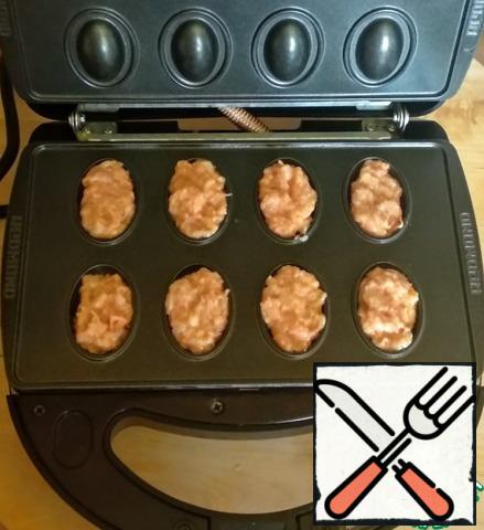 Insert the "nuts"panels into the multi-Baker. Turn it on, wait for the green light to light up and you can cook. Fill the lower cells with minced meat, about 1 teaspoon each.