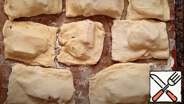 Brush the edges with beaten chicken egg. Wrap in an envelope, pinch the edges and transfer to a baking sheet. We do the same with the remaining parts and the second layer of dough.