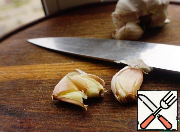 Two cloves of garlic are crushed with a knife. Don't clean it.