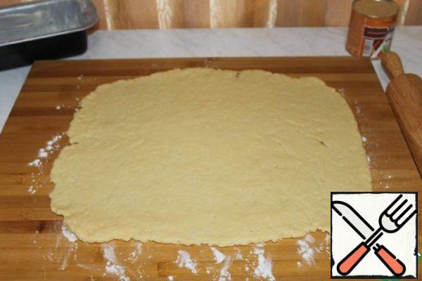 On a floured surface, roll out the dough into a rectangular layer.