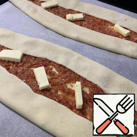 Take the pide by the edges and carefully transfer to a baking sheet covered with baking paper. Top with slices of sliced butter.